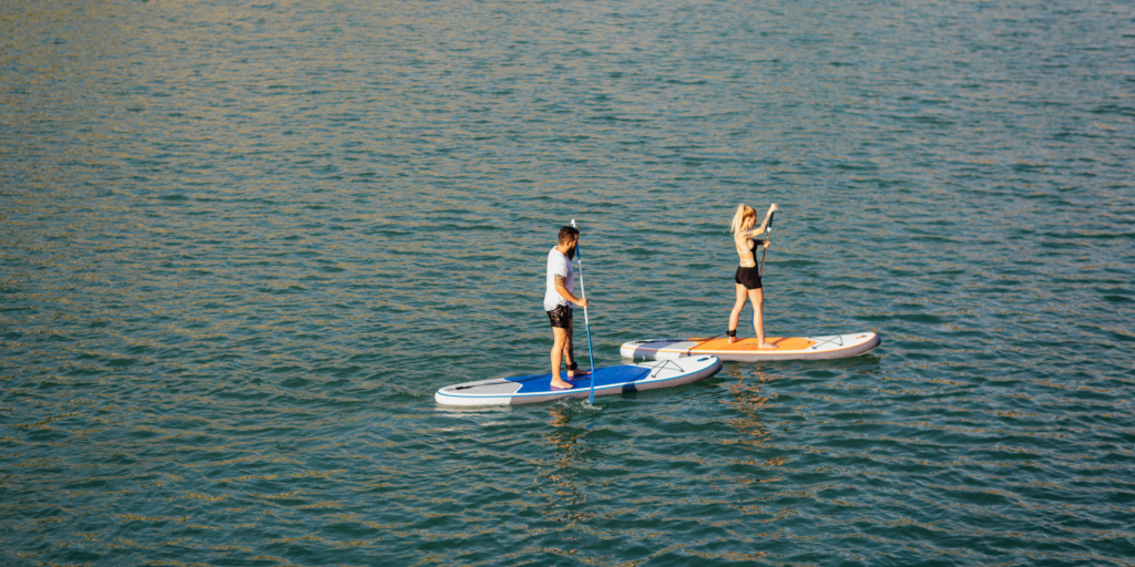 Image of two people in a river paddleboarding.