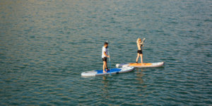 Image of two people in a river paddleboarding.